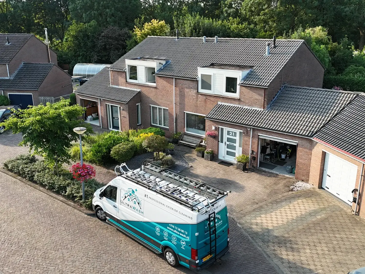 Een van onze turquoise Ultra Wash-bussen bij een woning, gezien vanuit de lucht