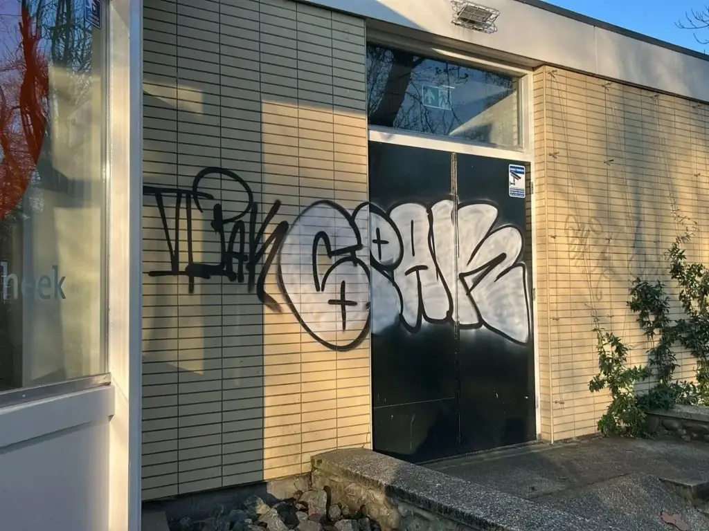 Graffiti op de deur en gevel van een bibliotheekpand voor de reiniging