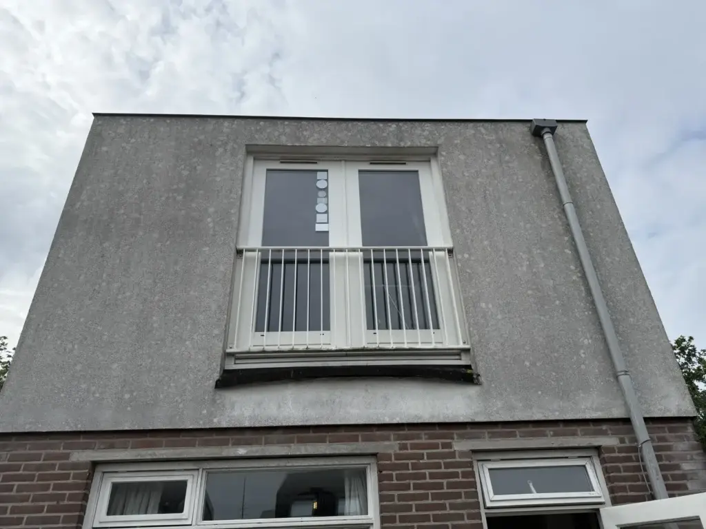 Vervuild grijs stucwerk van een dakopbouw voor de gevelreiniging