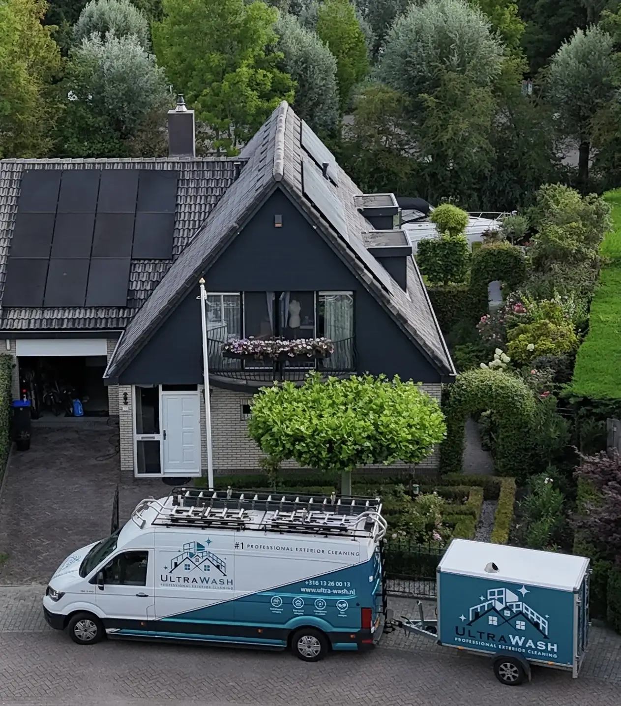 Een van onze turquoise Ultra Wash-bussen met aanhanger voor een woning, dronebeeld